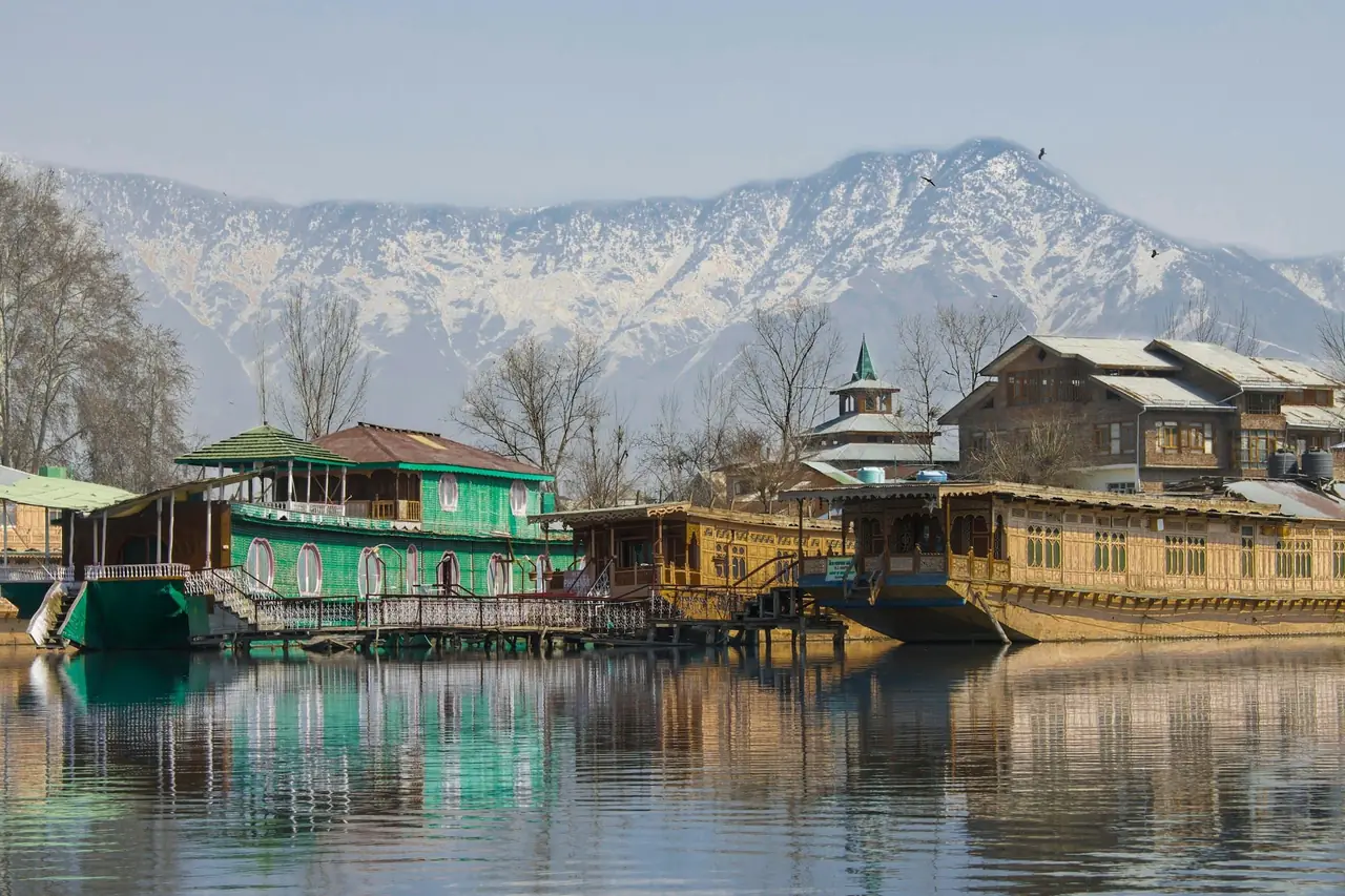 Carved wooden houseboats on Dal Lake with snow peaks behind