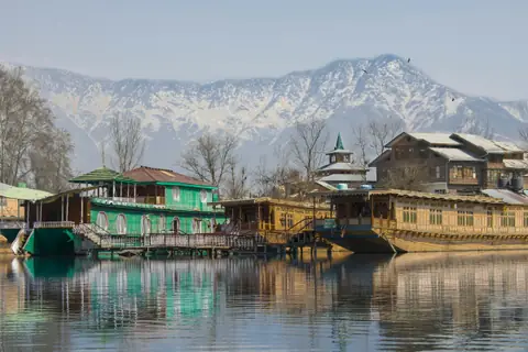 Carved wooden houseboats on Dal Lake with snow peaks behind