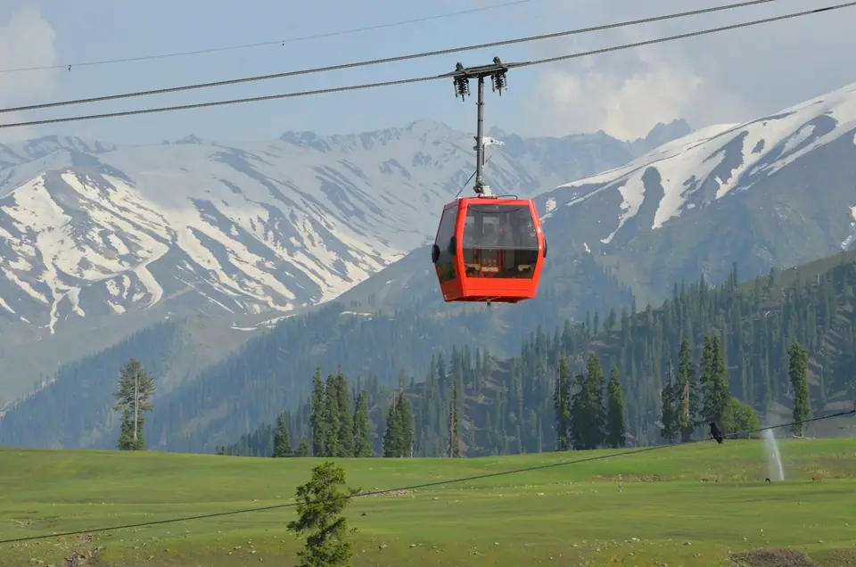 A red gondola cabin rising over the Gulmarg meadows